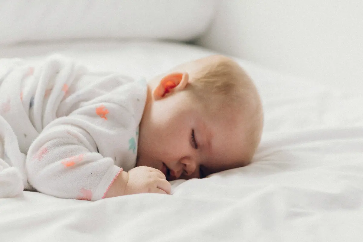 Baby im Bett mit Seitenschläferkissen